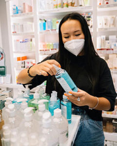 Woman working at pharmacy, displaying products.